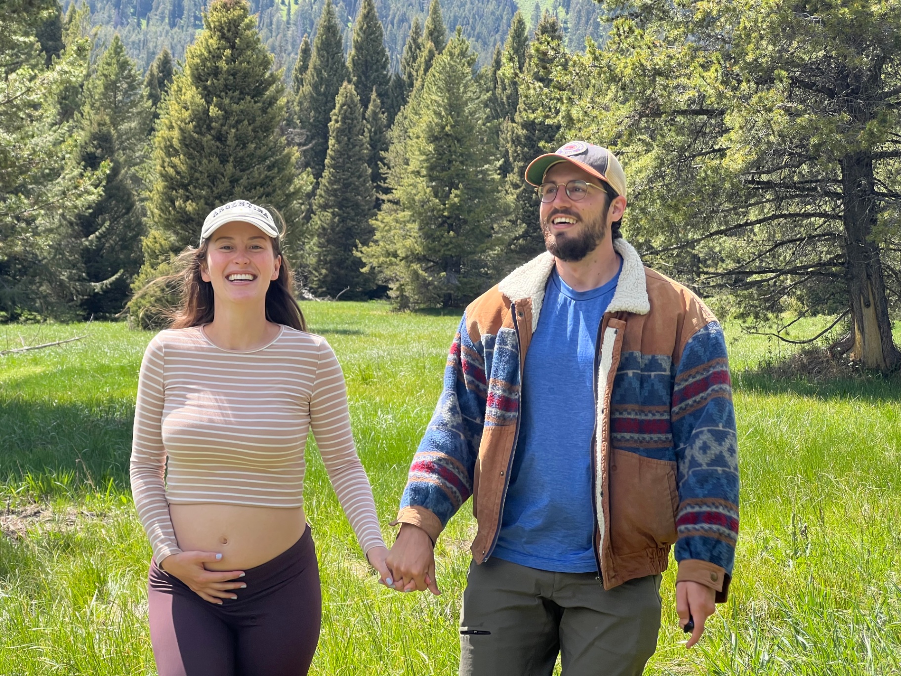 Emma and Sebastian holding hands in a mountain meadow